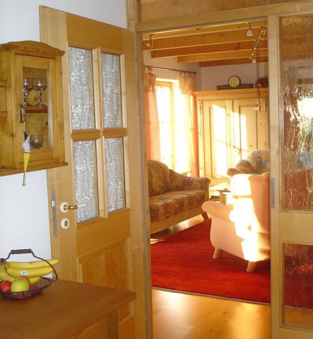 Wohnzimmer mit Holzbalkendecke und Parkett.Vier bodentiefe Sprossenfenster und noch zwei Türen und ein Kachelofen. Nicht einfach die Möbel zu stellen