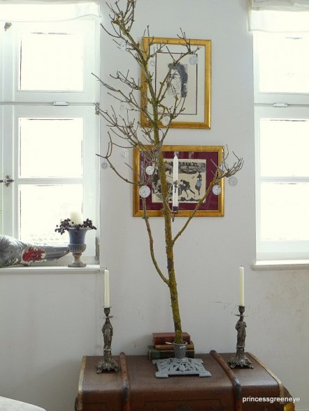 Ein knorriger Hollonderast in einem WEihnachtsbaumständer - dekoriert mit antiken Ziffernblättern und einem antiken Kerzenhalter, wie sie früher in de