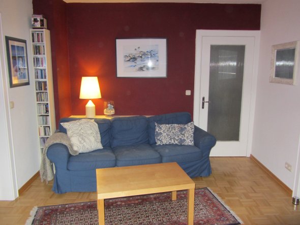 Unser blaues Sofa... vor der roten Wand. Die Ablage/Sideboard ist ein weißes Brett aus dem Bumarkt, schief abgesägt. Das Sofa hätte gerade nicht an di