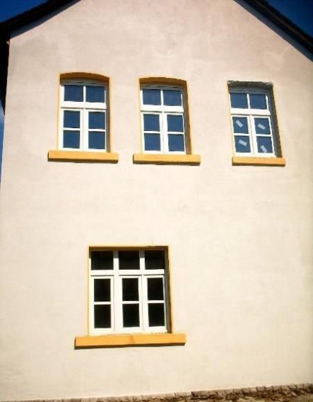 Ansicht auf die Südseite des Gebäudes. Dies ist auch die Wetterseite. Jahrelange Witterungseinflüsse haben die seinerzeit aus Holz hergestellten Fenst