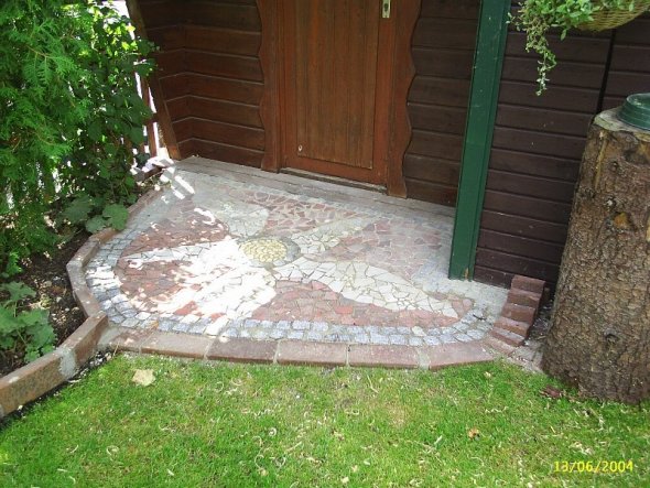 Hier haben wir aus Restmaterialien ein Mosaik vor die Gartenhütte gelegt.